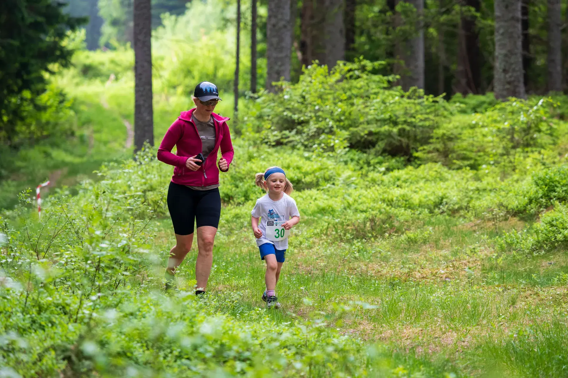 En vuxen och ett litet barn springer tillsammans under barnloppet, 2024