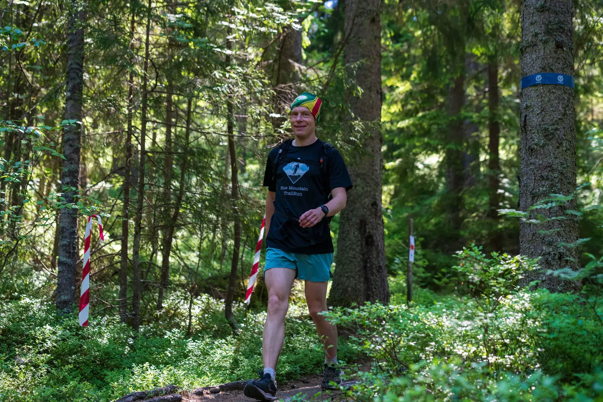 Glad funktionär i loppets tröja längs banan i granskogen, 2024