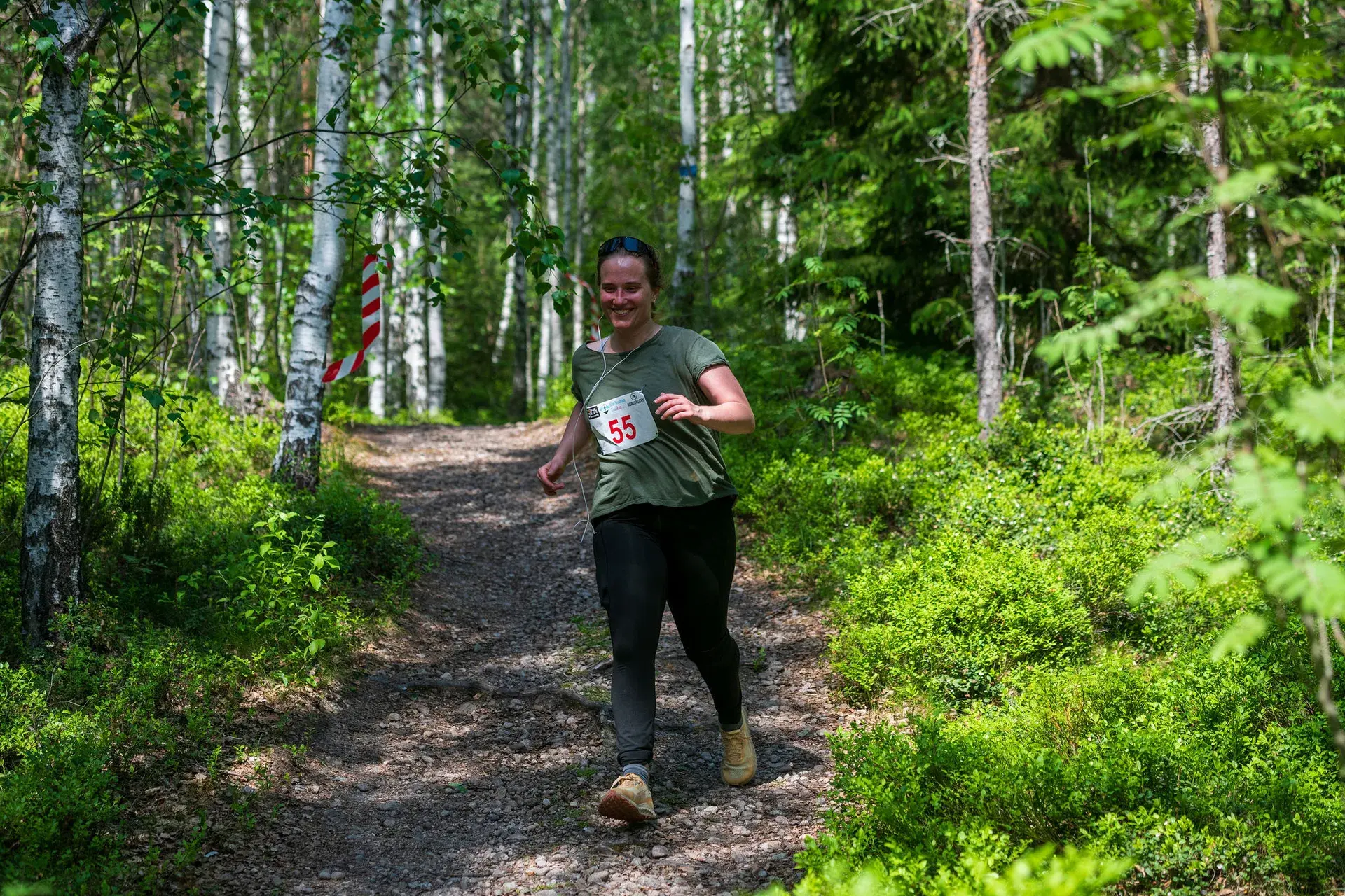 Leende löpare på väg nerför en grusad stig i björkskogen, 2024