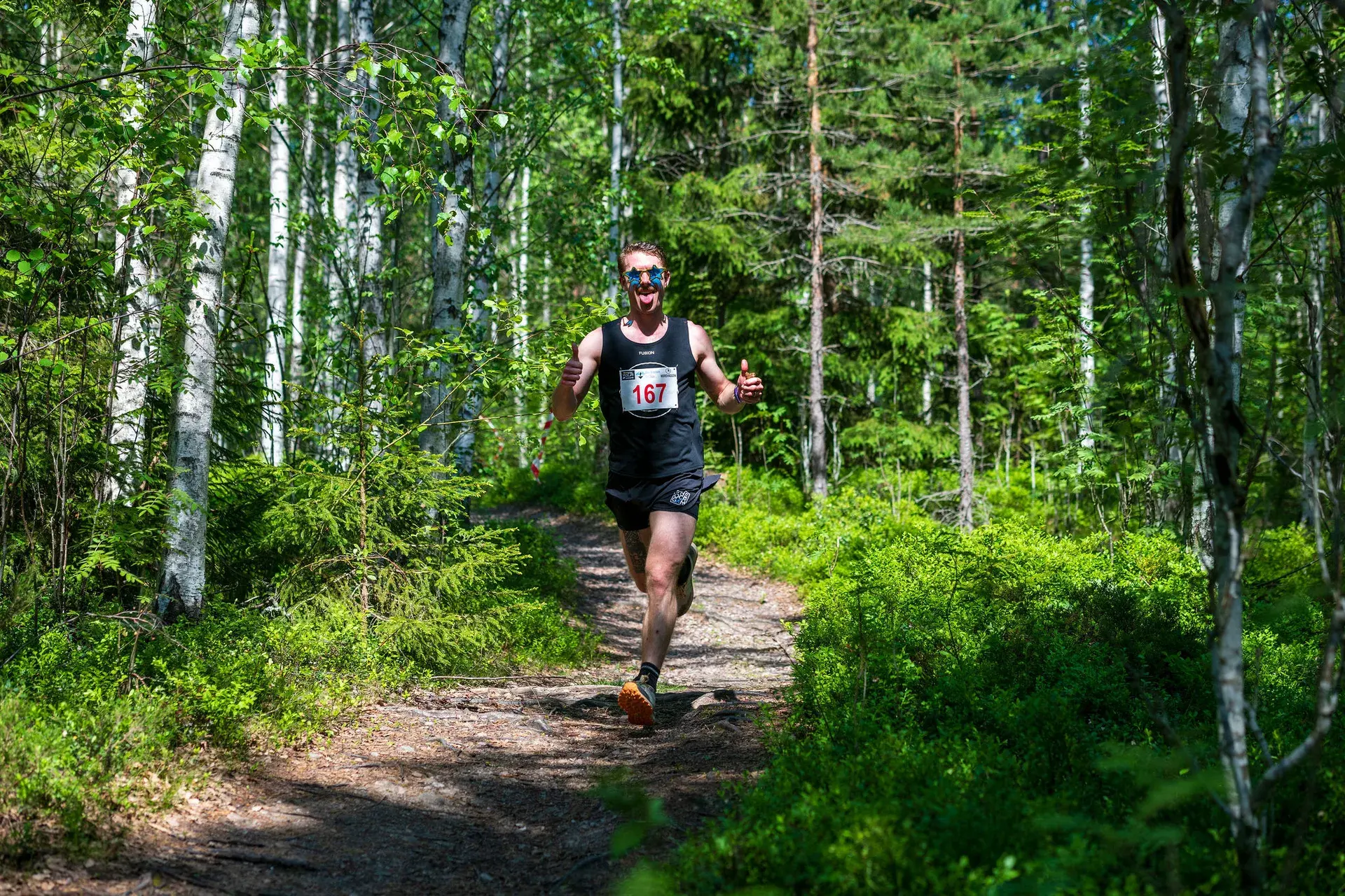 Löpare gör tummen upp på stigen genom björkskogen, 2024