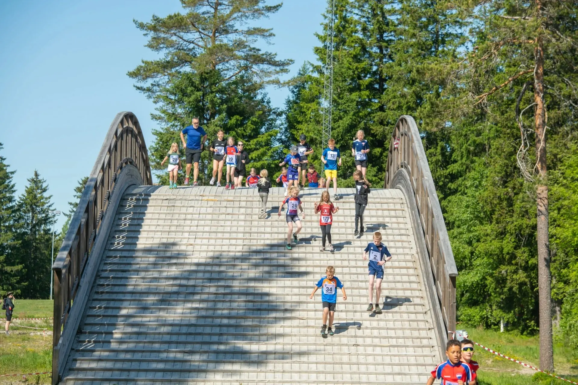 Barnloppet 2023: barn springer nerför den stora träbron i solen